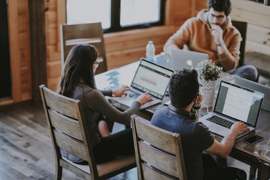 Small team planning an event around a wooden table with laptop and notes
